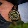 Close-up of a person's wrist wearing a detailed wristwatch with a black and gold face.