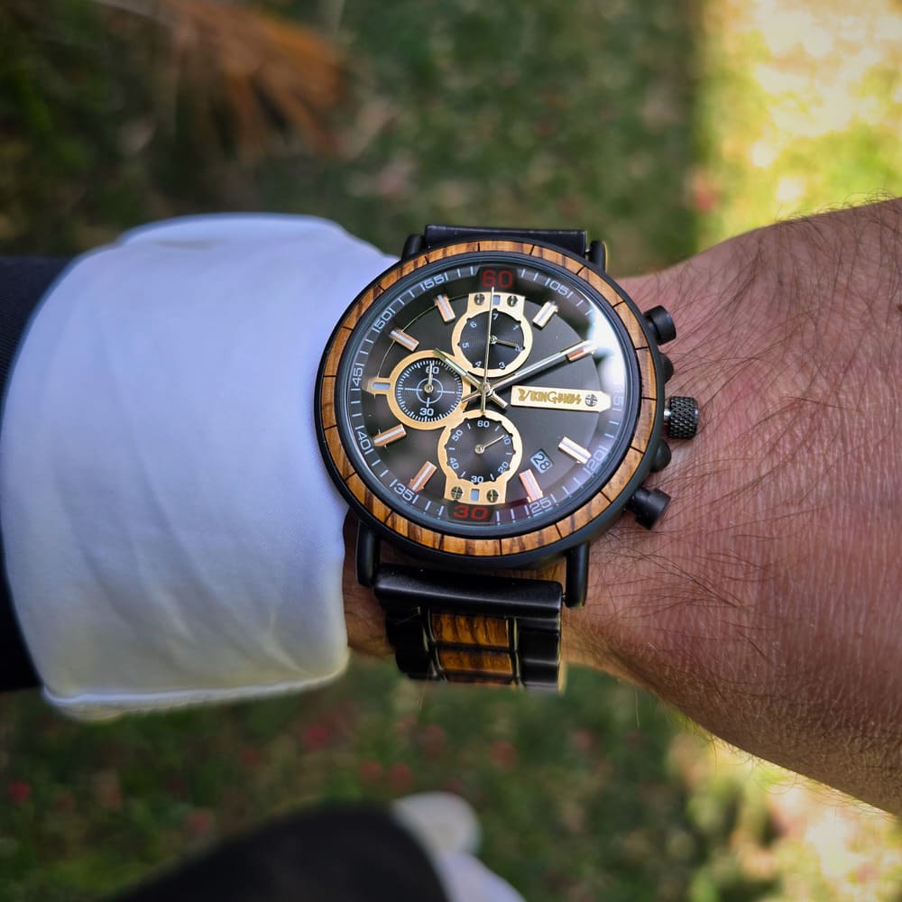 Close-up of a wrist wearing a detailed wristwatch with a blurred natural background