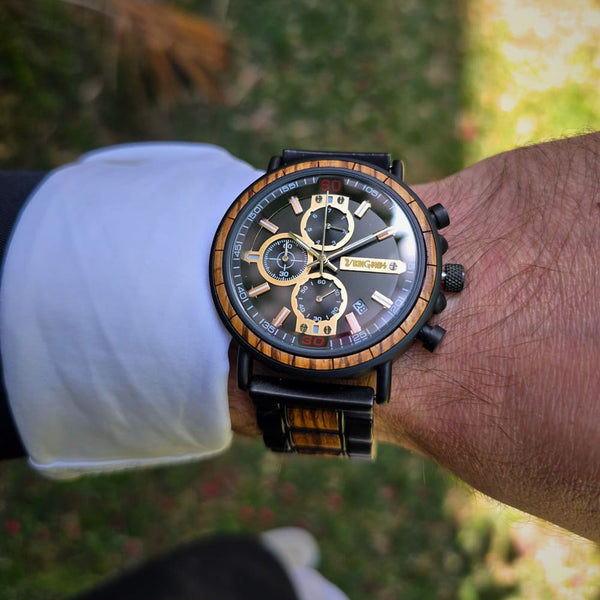 Close-up of a wrist wearing a detailed wristwatch with a blurred natural background