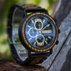 Black and gold wooden chronograph watch on wrist showing adjustable black link strap