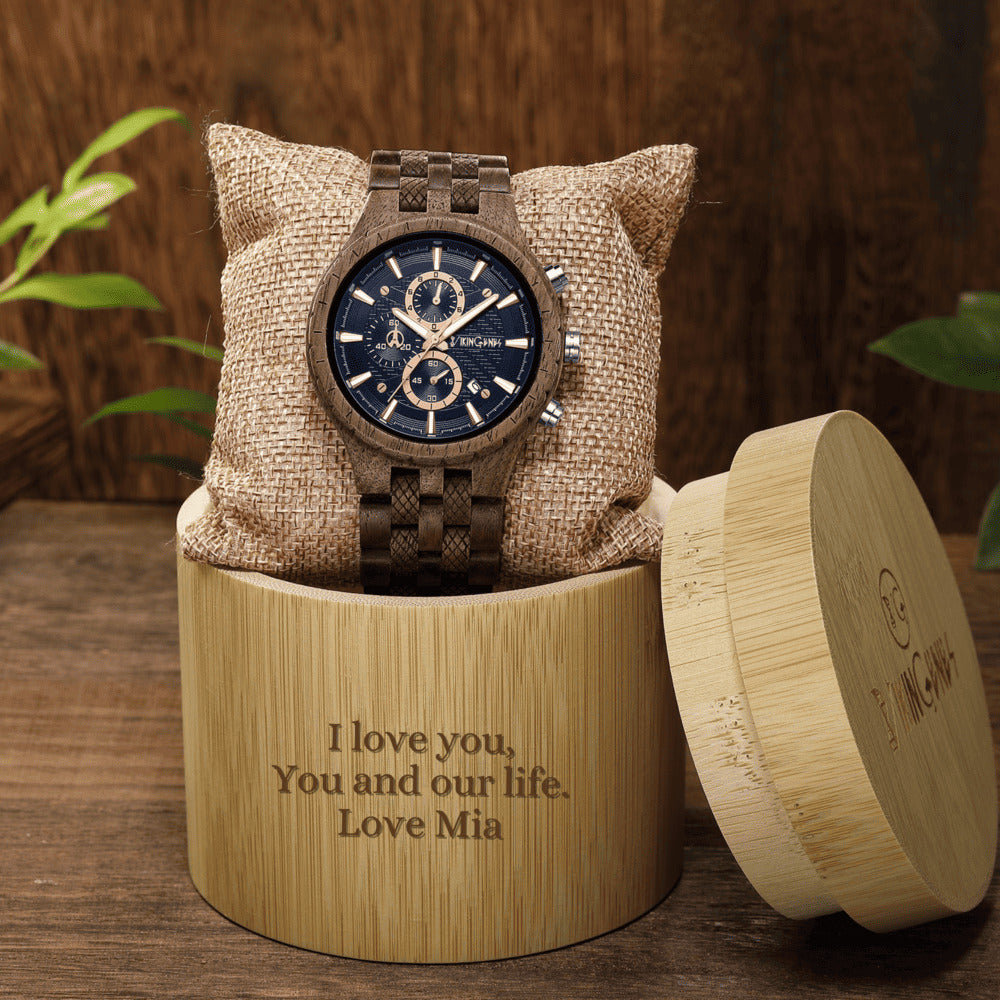 Watch in a wooden box with engraved message on a wooden surface