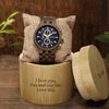 Watch in a wooden box with engraved message on a wooden surface