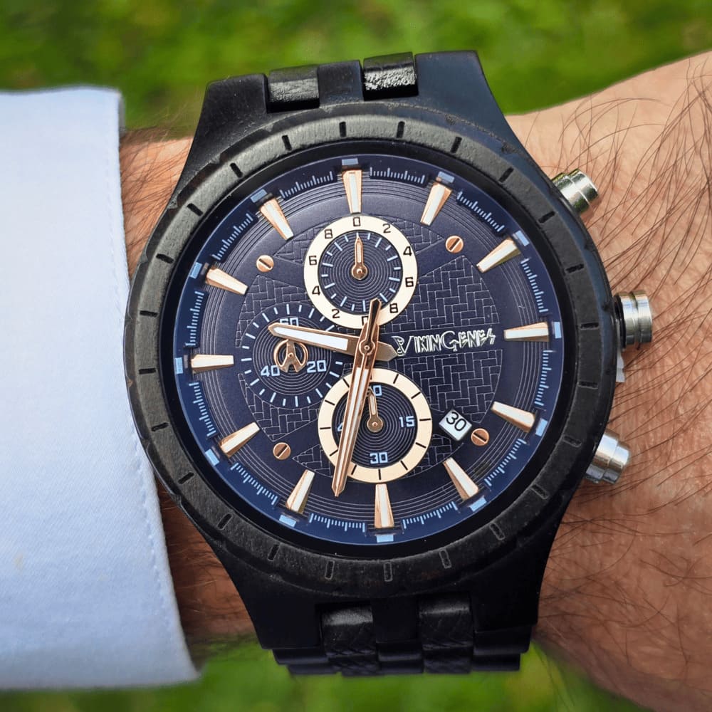 Black wristwatch with a detailed face on a wrist against a natural background