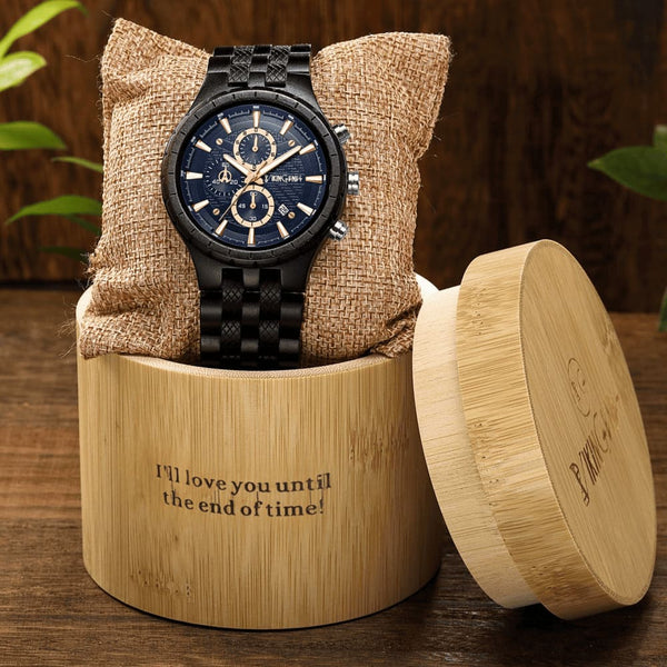 Black wristwatch with blue face in a wooden box on a wooden surface