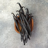 Vanilla beans in a wooden bowl on a gray surface