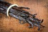 Bunch of vanilla beans tied together on a wooden surface. Discover the rich, creamy flavor of our USDA Organic Grade A Madagascar Vanilla Beans. Perfect for baking, homemade vanilla extract, and gourmet desserts, these Bourbon vanilla pods are the gold standard for quality.
