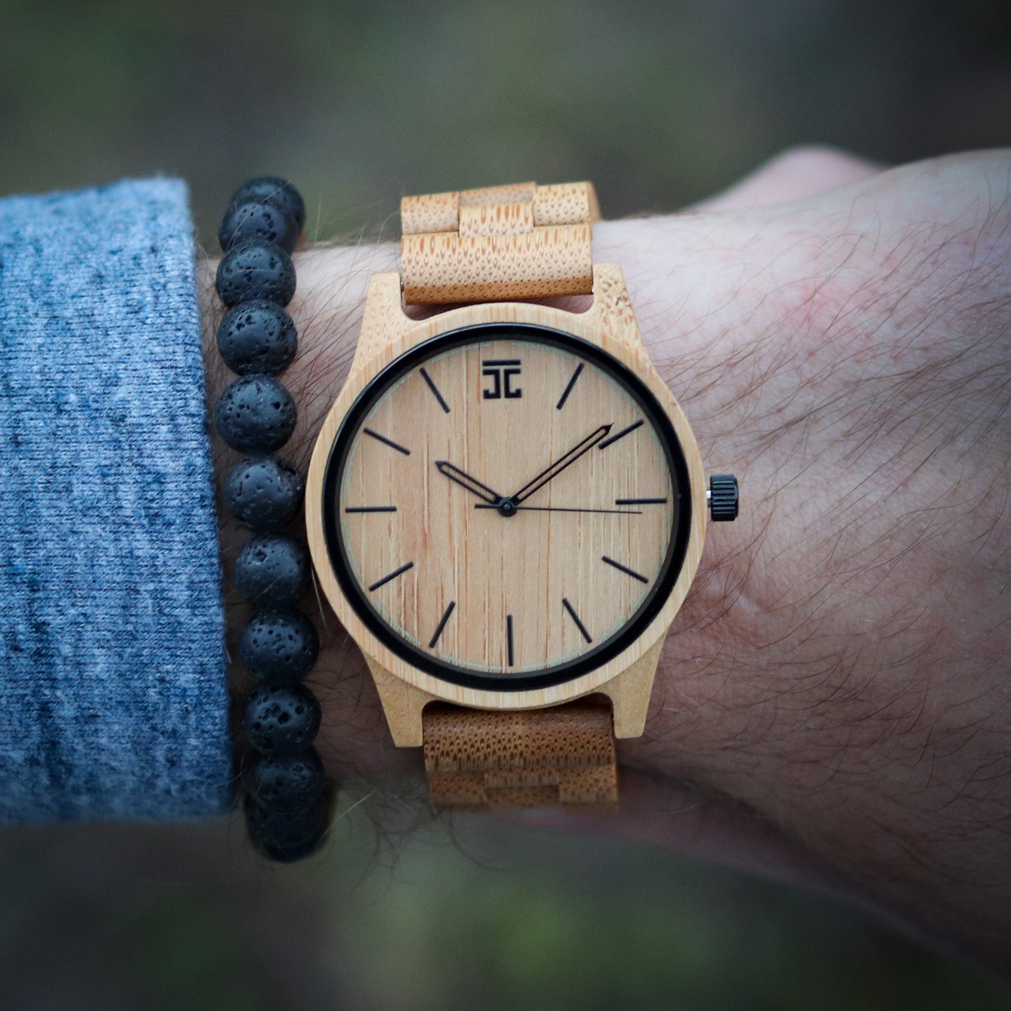 Wooden watch with cork strap on wrist against a blurred natural background