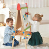 Two children playing with a colorful wooden easel in a home setting.