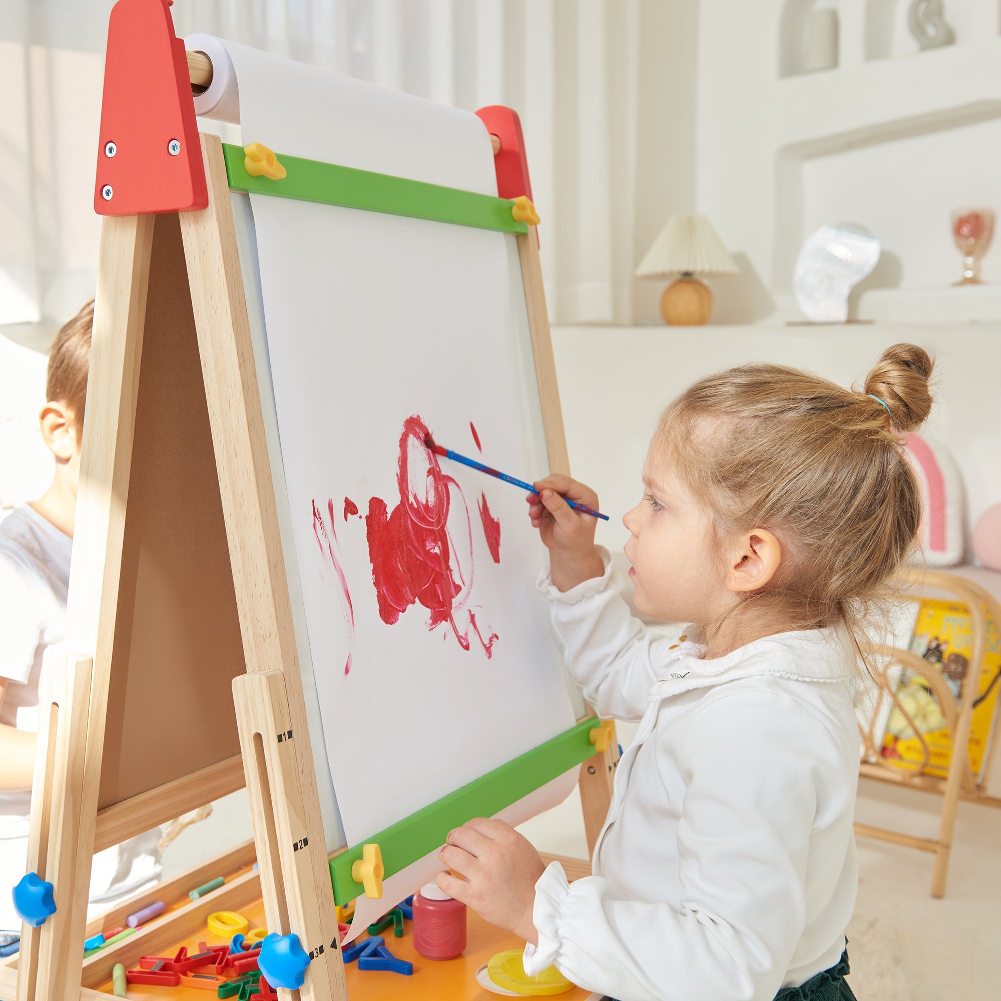 Child painting on a wooden easel with colorful paint and brushes.
