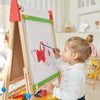 Child painting on a wooden easel with colorful paint and brushes.