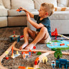 Child playing with a wooden toy train set on the floor.
