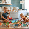 Two children playing with a wooden train set in a living room.
