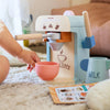 Children's toy coffee machine with a pink cup on a carpeted floor.