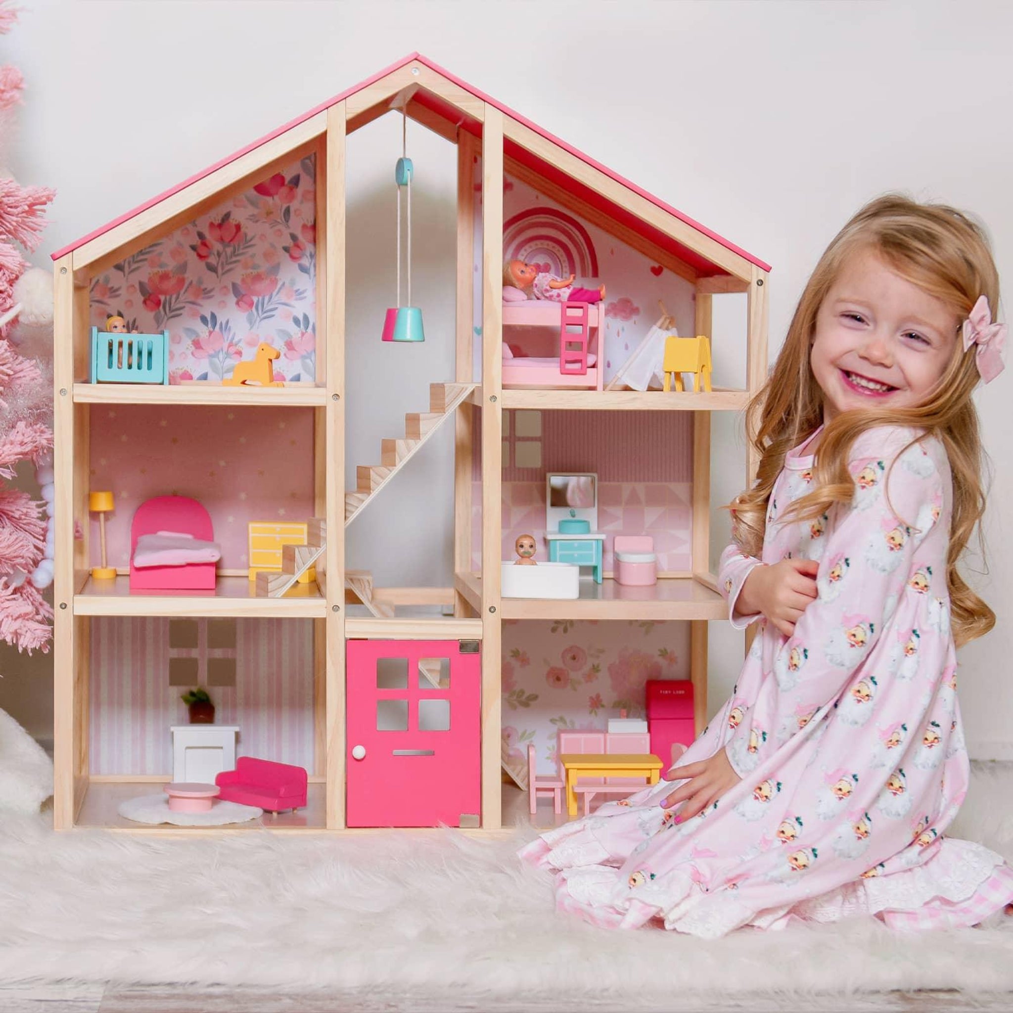 Child with a wooden dollhouse featuring pink and floral details