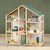 Wooden dollhouse with detailed interior and furniture on a textured surface.