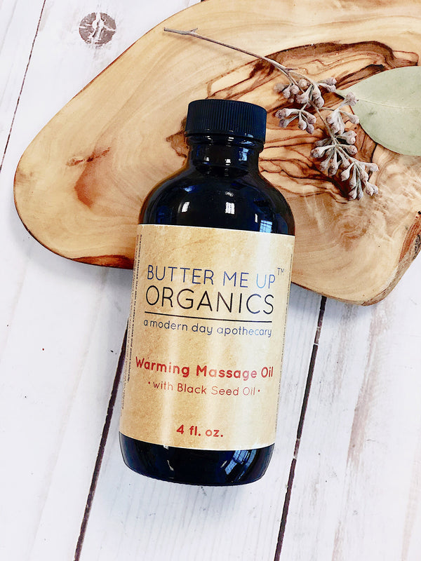 4 oz glass bottle of Butter Me Up Organics Organic Warming Massage Oil for muscle ache relief, made with Black Cumin Oil, Arnica, Calendula, and Cinnamon Leaf essential oil