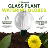 Blumat glass plant watering globe with a yellow flower and soil in the background