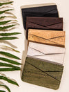 Set of four cork wallets in different colors on a light background with green leaves.