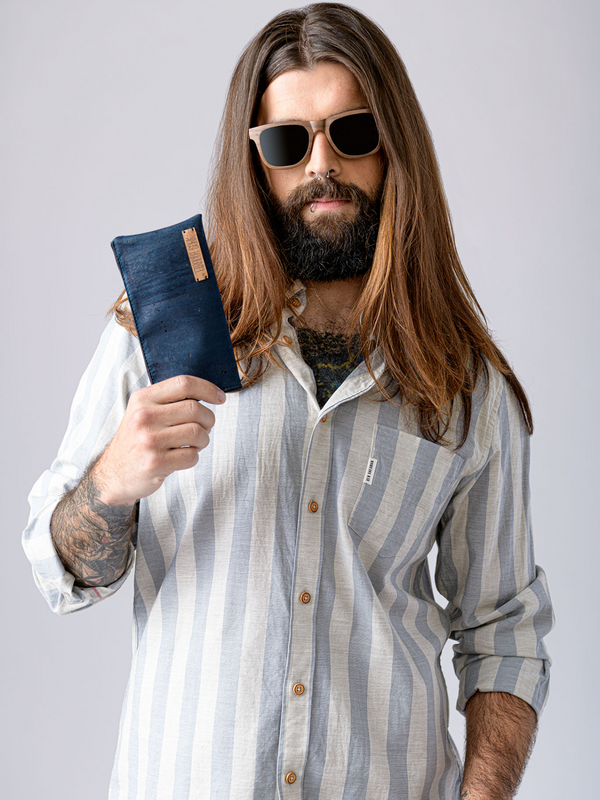 Man with long hair and beard holding a blue pouch against a gray background