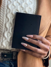 Hand holding a black wallet on a textured surface