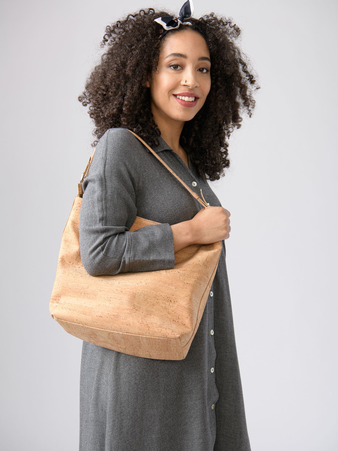 Woman holding a beige tote bag against a plain background