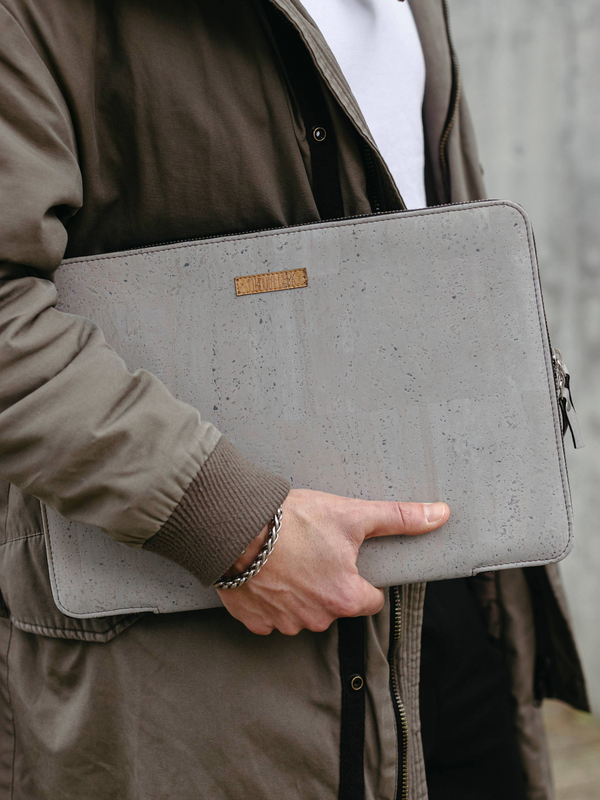 Person holding a gray laptop sleeve with a brand label.