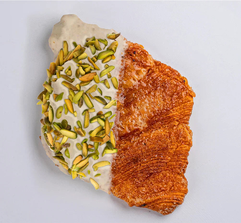 Pastry with white cream and green pistachios on a light gray background