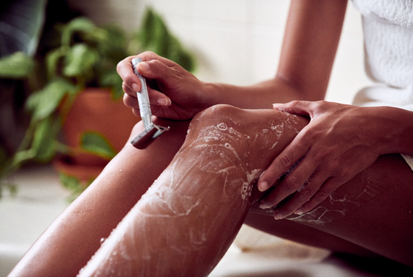 Close-up of Desesh metal safety razor and solid shave soap being used to shave legs – eco-friendly shaving