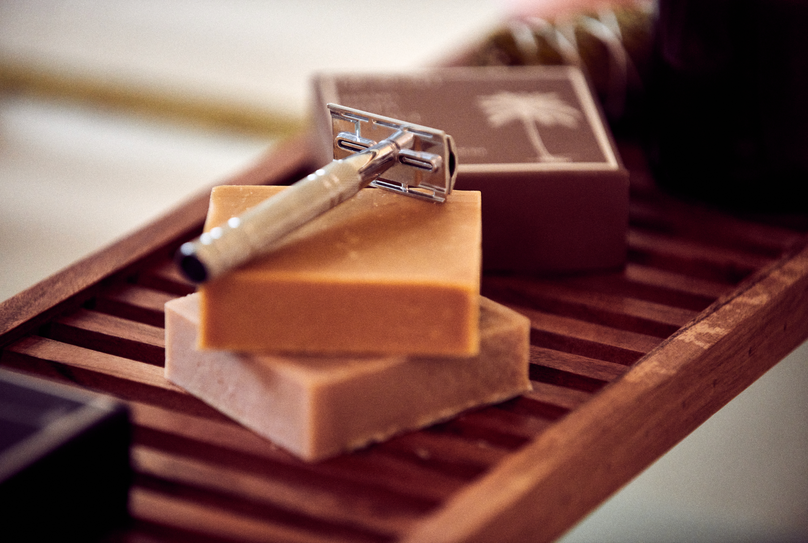 Desesh metal safety razor and solid shave soap resting beside a bathtub – plastic-free personal care routine