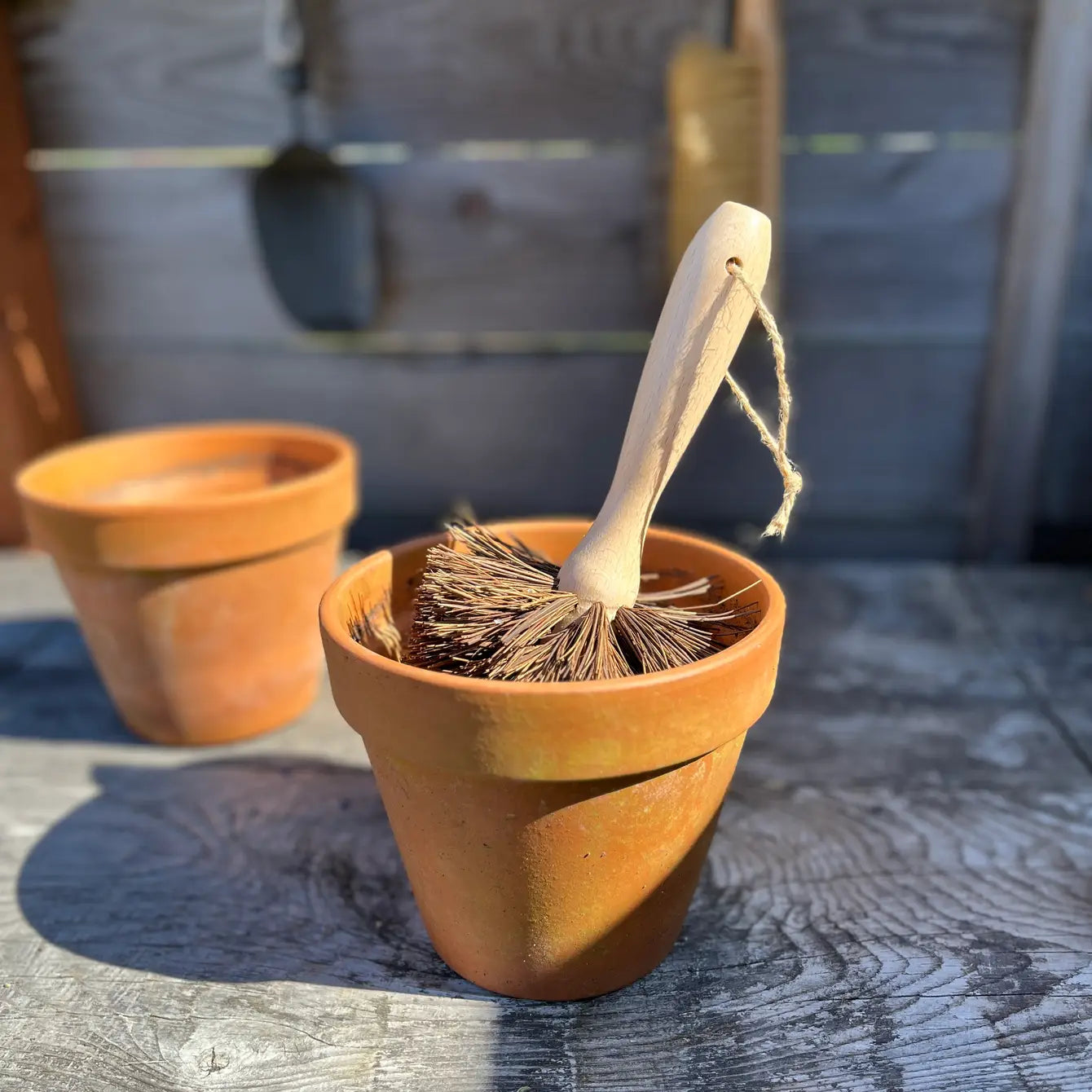 Terracotta pot with a broom inside on a wooden surface