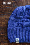 Blue knit beanie on a wooden surface with 'Blue' text above it