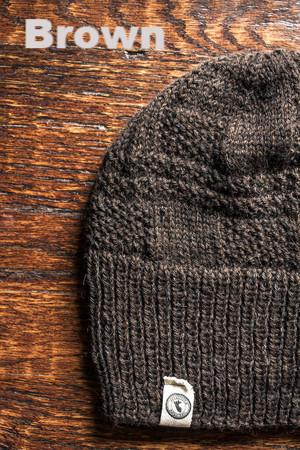 Brown knit beanie on a wooden surface with 'Brown' text above.