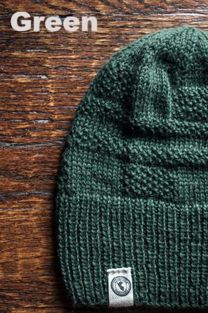 Green knit beanie on a wooden surface with 'Green' text above.
