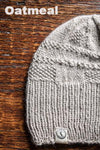 Gray knit beanie on a wooden surface with 'Oatmeal' text above
