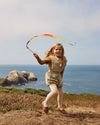Child playing with a ribbon on a coastal cliffside