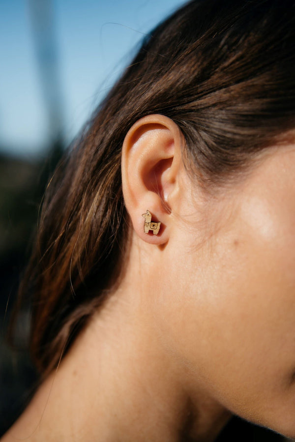 Close-up of a person wearing a gold earring outdoors with a blurred background