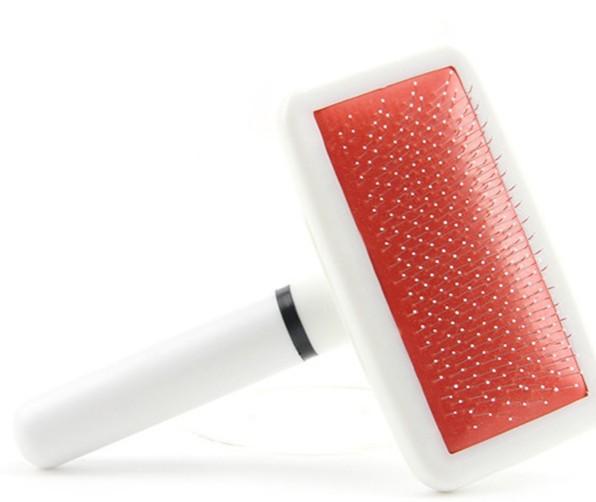 Pet grooming brush with red rubber pad on a white background