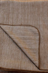 Close-up of a brown textured rug with a folded corner.