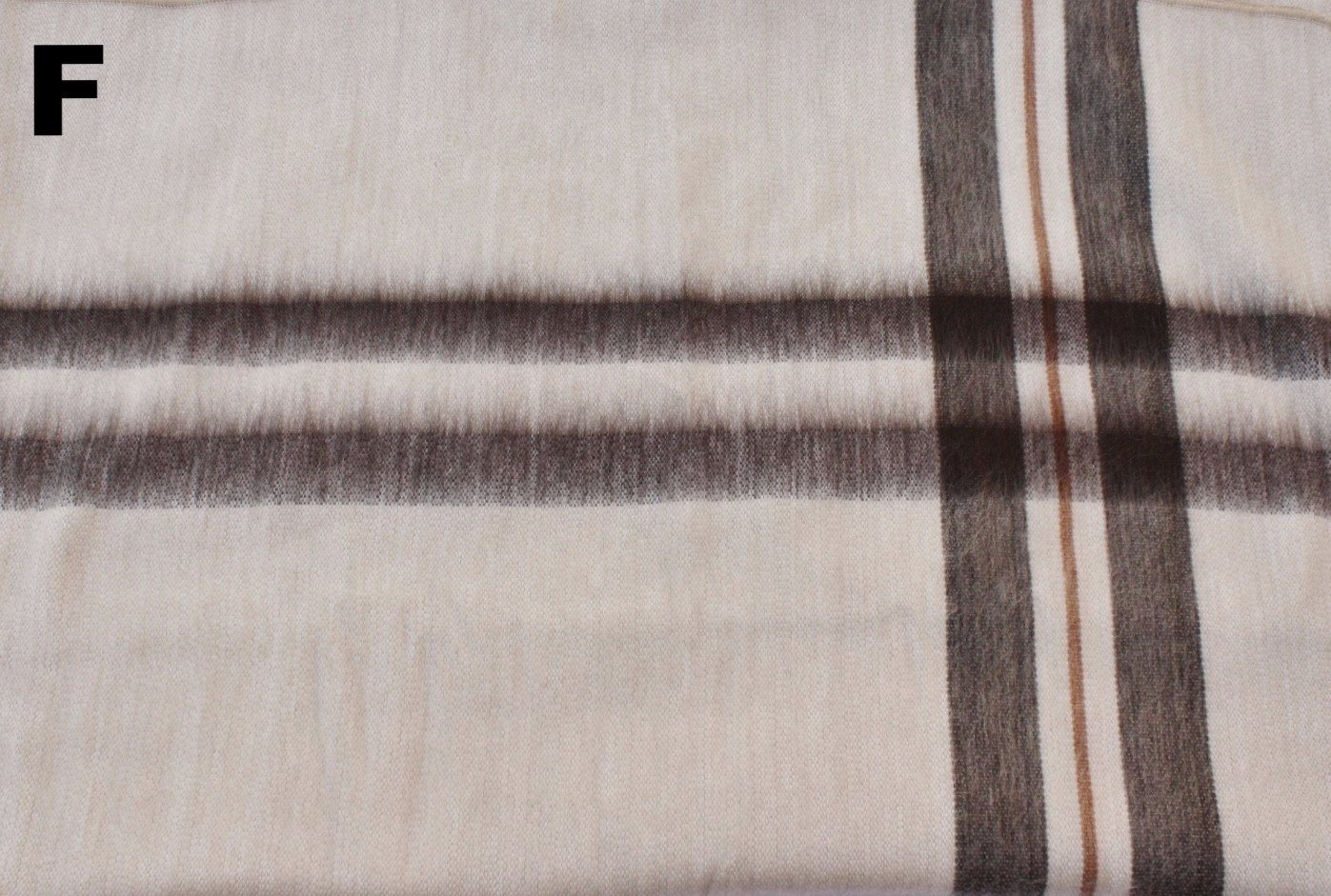 Close-up of plaid fabric with brown and beige colors on a white background.