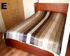 Bed with striped bedding in a room with wooden furniture.