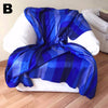 Blue striped blanket draped over a white chair in a room with wooden flooring.