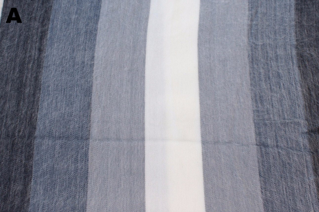 Multiple striped alpaca bed blanket colour options laid out, handcrafted in Otavalo Ecuador