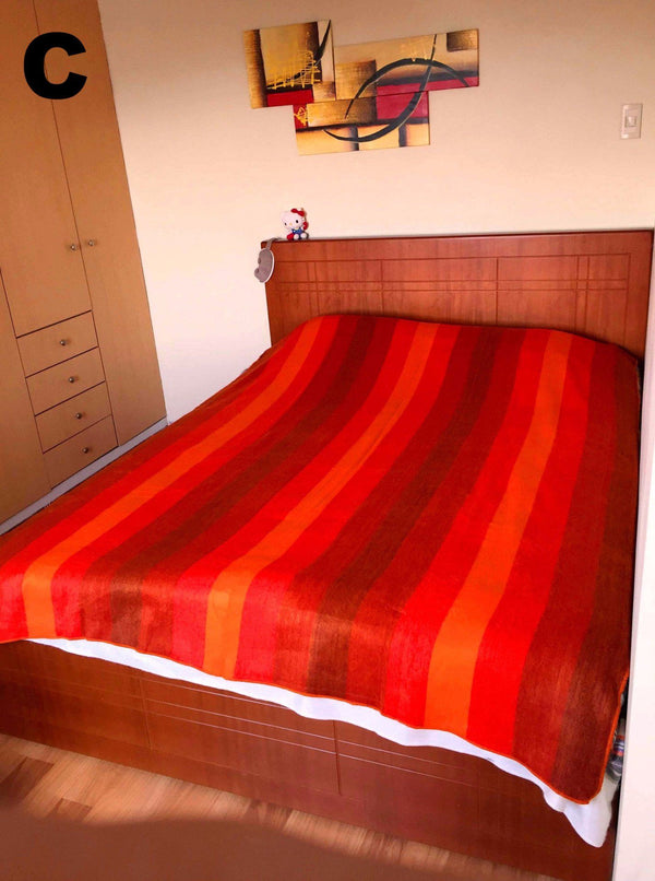 Bed with red striped bedding in a room with wooden furniture and a painting on the wall.