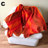 Orange striped blanket draped over a white chair on a wooden floor.