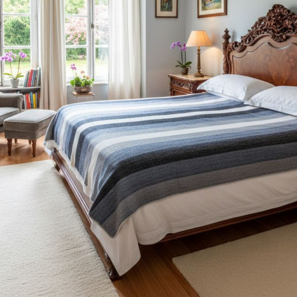 Striped alpaca bed blanket draped over a bed, showing full size and colourful stripe pattern