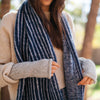 Person wearing a blue and white striped alpaca scarf with a blurred outdoor background
