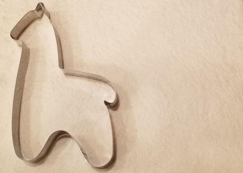 Metallic horse-shaped cookie cutter on a beige background