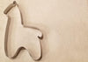 Metallic horse-shaped cookie cutter on a beige background