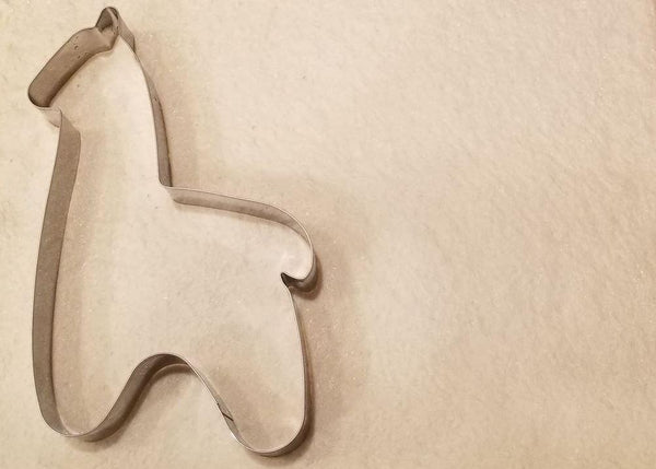 Metallic horse-shaped cookie cutter on a beige background