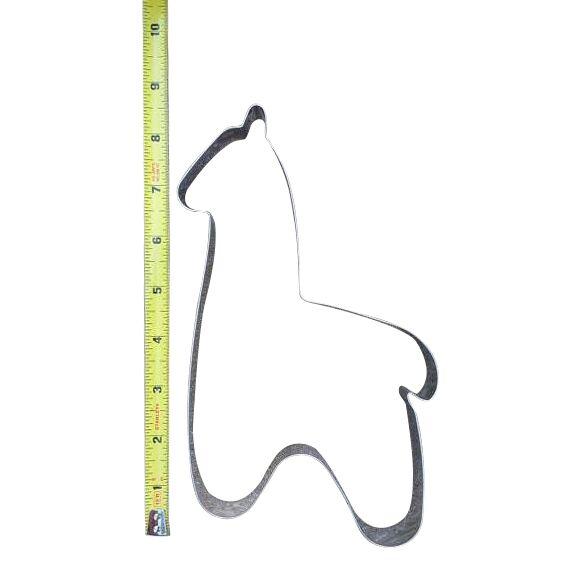 Metallic dog bone-shaped cookie cutter with a ruler for scale on a white background